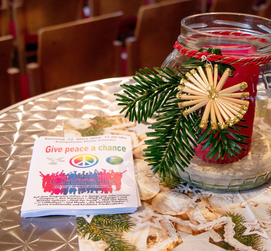 Plakat-Flyer auf dekorierten Tisch für Friedenskonzert-Werbung am 22. März 2026